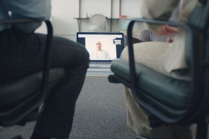 Duas pessoas acompanham uma consulta on-line em um laptop, em um ambiente profissional.