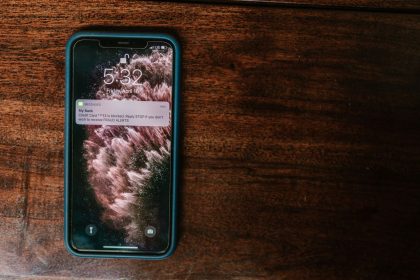 Celular exibindo um alerta bancário sobre uma superfície de madeira