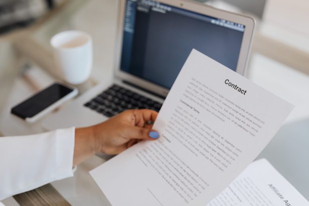 Pessoa segura um documento jurídico ao lado de um laptop durante uma sessão de trabalho.