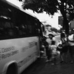 Pessoas embarcam em um ônibus urbano no Rio de Janeiro, em uma fotografia em preto e branco.
